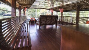 Un espace extérieur abrité, doté de bancs en bois et d’une table, offrant une vue sur une étendue d’eau.