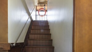 Un escalier en bois avec une rampe métallique menant à un palier.