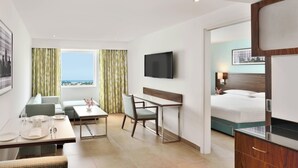 A hotel room with a bed, a desk, a chair, a TV, and a view of the city. - Fairfield by Marriott Chennai OMR (Chennai)