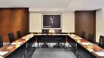 Un salón de conferencias con una larga mesa, sillas y una pantalla que muestra a un bailarín.