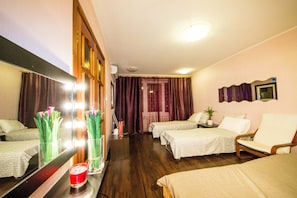 Two single beds and a comfortable seating area in a well-appointed room with a mirrored wardrobe and a small table.