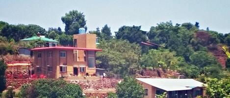 Un edificio de dos pisos con techo rojo y un tanque de agua en la parte superior.