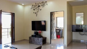 A living room with a flat-screen TV, a marble coffee table, and a dining area with a table and chairs.