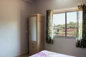 A bedroom with a bed, a wardrobe, and a window with curtains. - GuestHouser 5 BHK Bungalow 4435 (Mahabaleshwar)