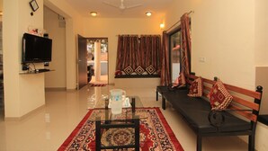 A living room with a sofa, a coffee table, a TV, and a patterned rug.