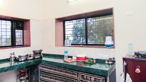 A kitchen with a green countertop, a stove, a sink, and a window with a view of trees.