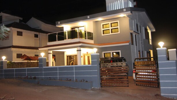 A two-story house with a balcony, a garage, and a gated entrance.