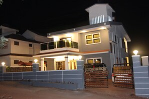 Uma casa de dois andares com varanda, garagem e entrada protegida por portão.