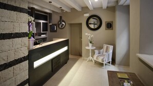 A reception area with a reception desk, a clock, a mirror, and a chair. - Locanda in Borgo Garni & Wellness (Borgo Valsugana)