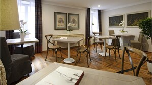 A dining area with wooden tables and chairs, a lamp, and artwork on the walls. - Locanda in Borgo Garni & Wellness (Borgo Valsugana)