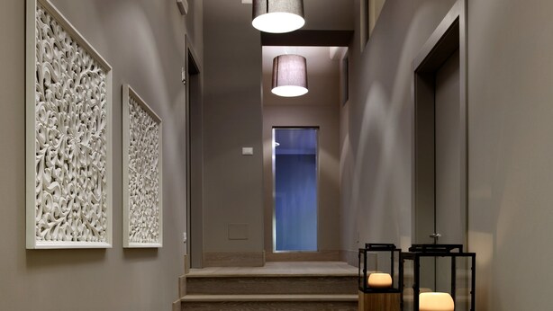 A modern hallway with a staircase, wooden floor, and decorative wall panels. - Locanda in Borgo Garni & Wellness (Borgo Valsugana)