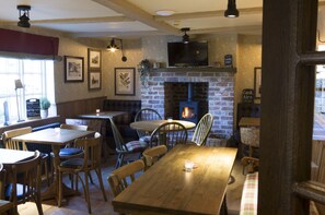 Un pub acogedor con muebles de madera, una chimenea de ladrillo y un televisor colocado encima.
