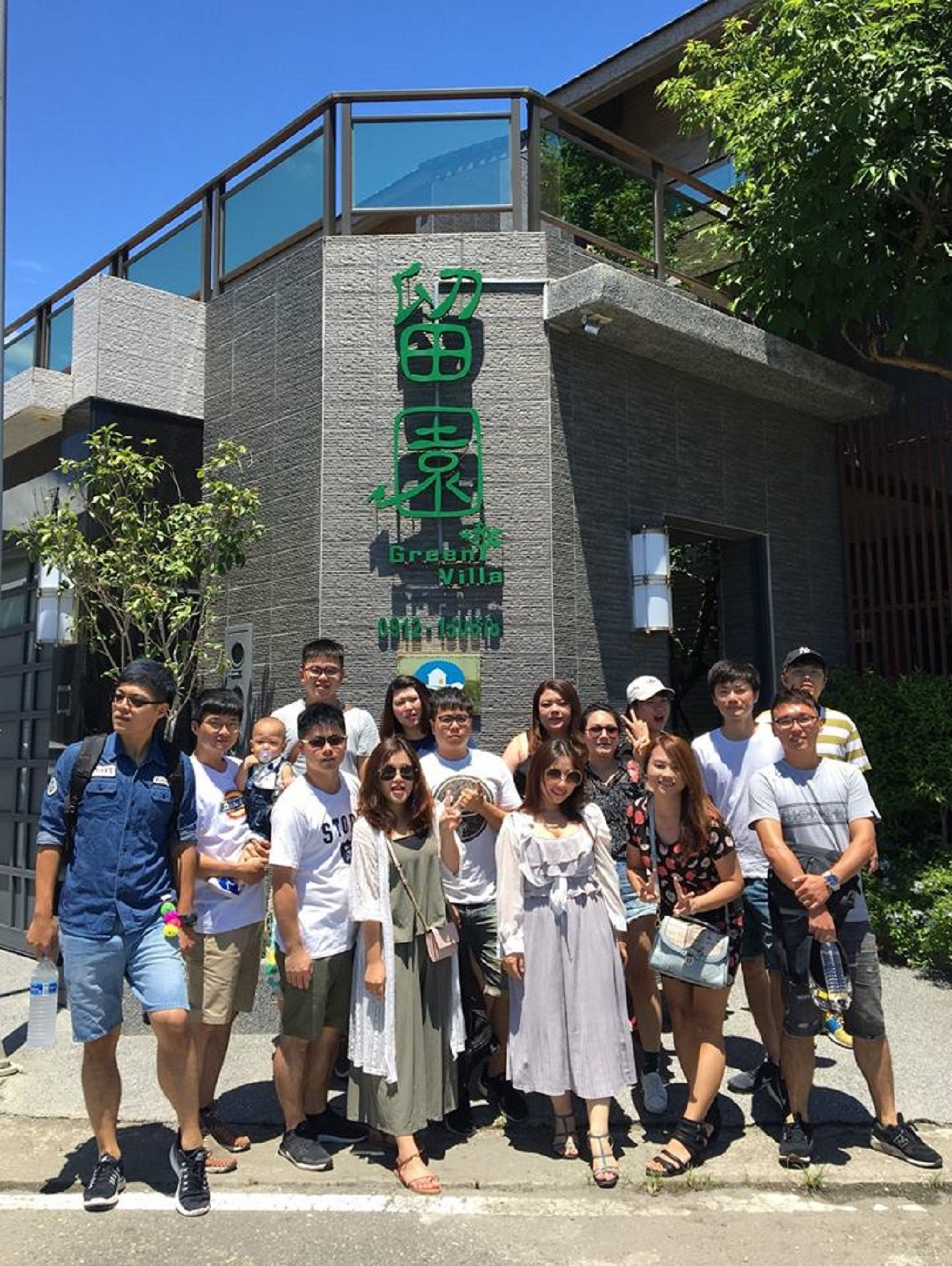 Un grupo de personas frente a un edificio con un letrero que dice "Green Villa".