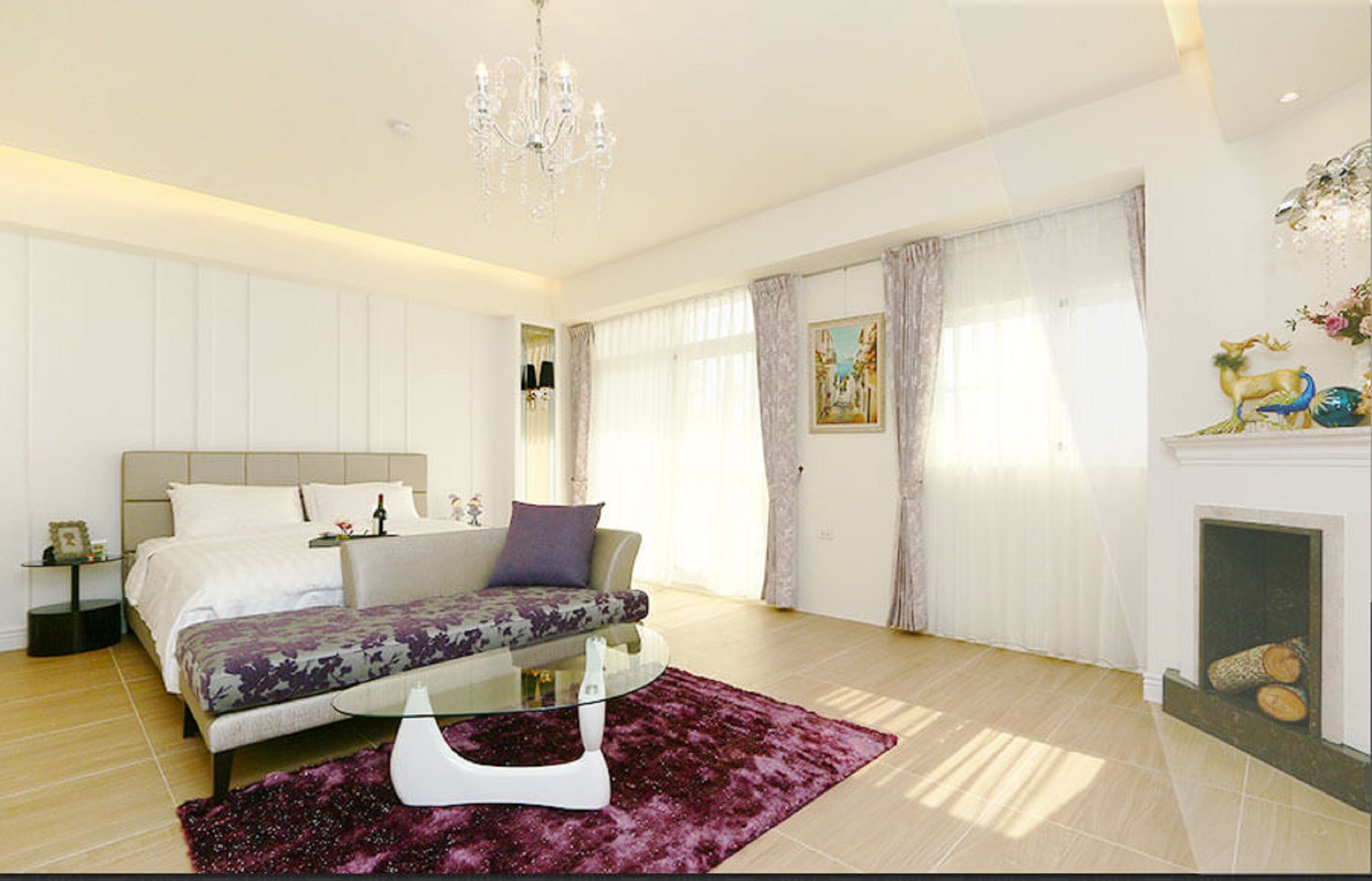 Un dormitorio moderno con una cama, una mesa de centro de vidrio y una chimenea.