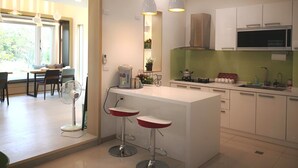 A modern kitchen with a central island, bar stools, a microwave, and a stove.