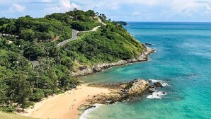A coastal landscape with a winding road, a beach, and clear turquoise waters. - Inspire Villas Phuket (Rawai)