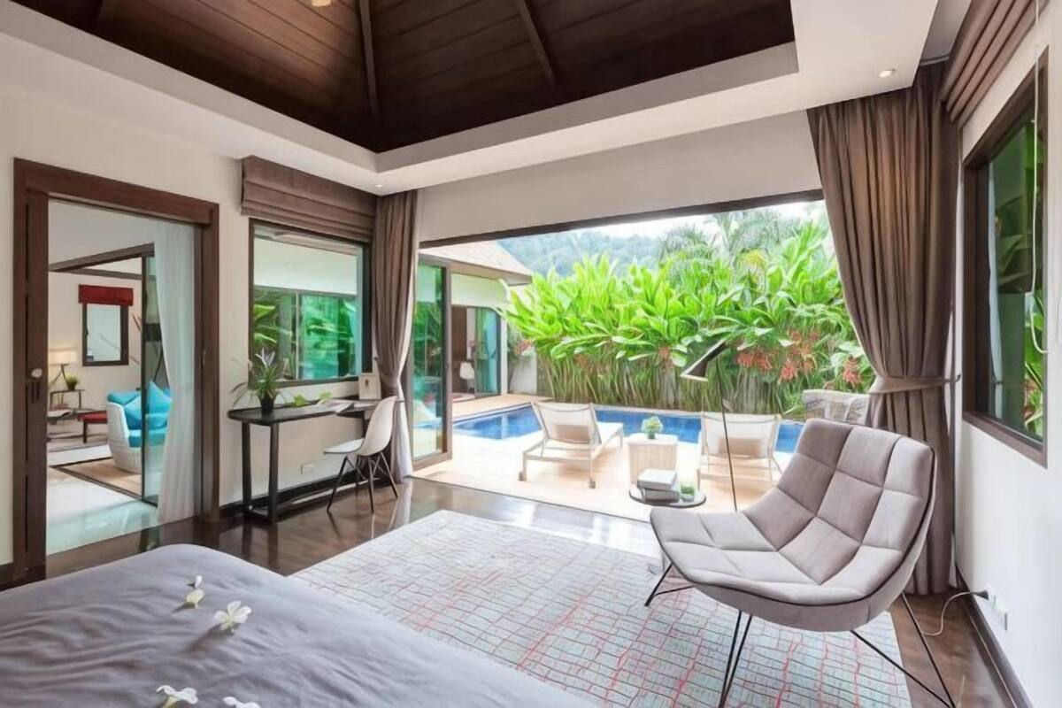 Un dormitorio moderno con una cama grande, un escritorio y vistas a una piscina y jardín.