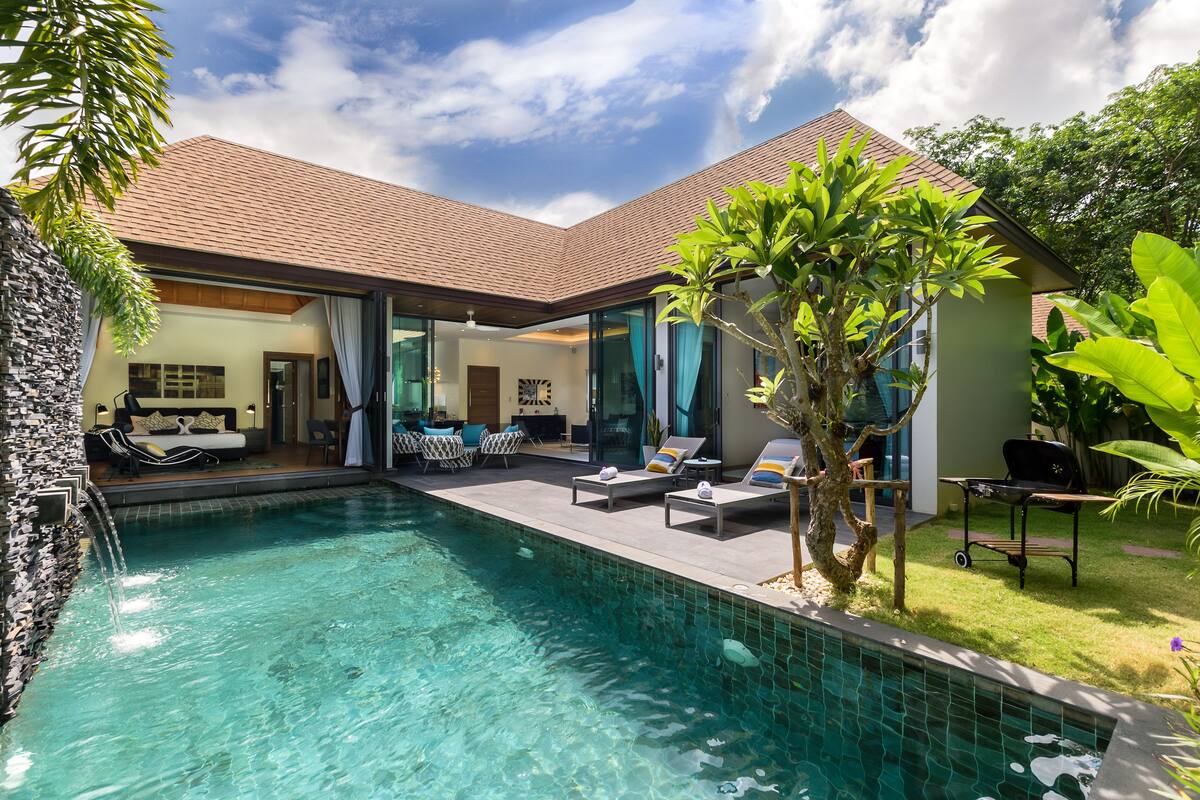 Una casa moderna con piscina, mobiliario exterior y un jardín cuidado.