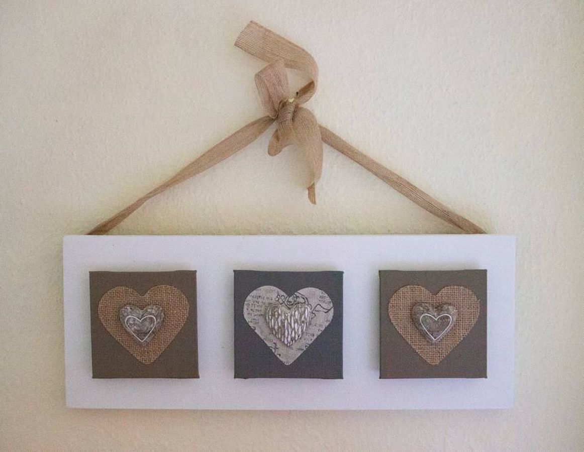 A wall-mounted display with three square frames, each containing a heart-shaped cutout.