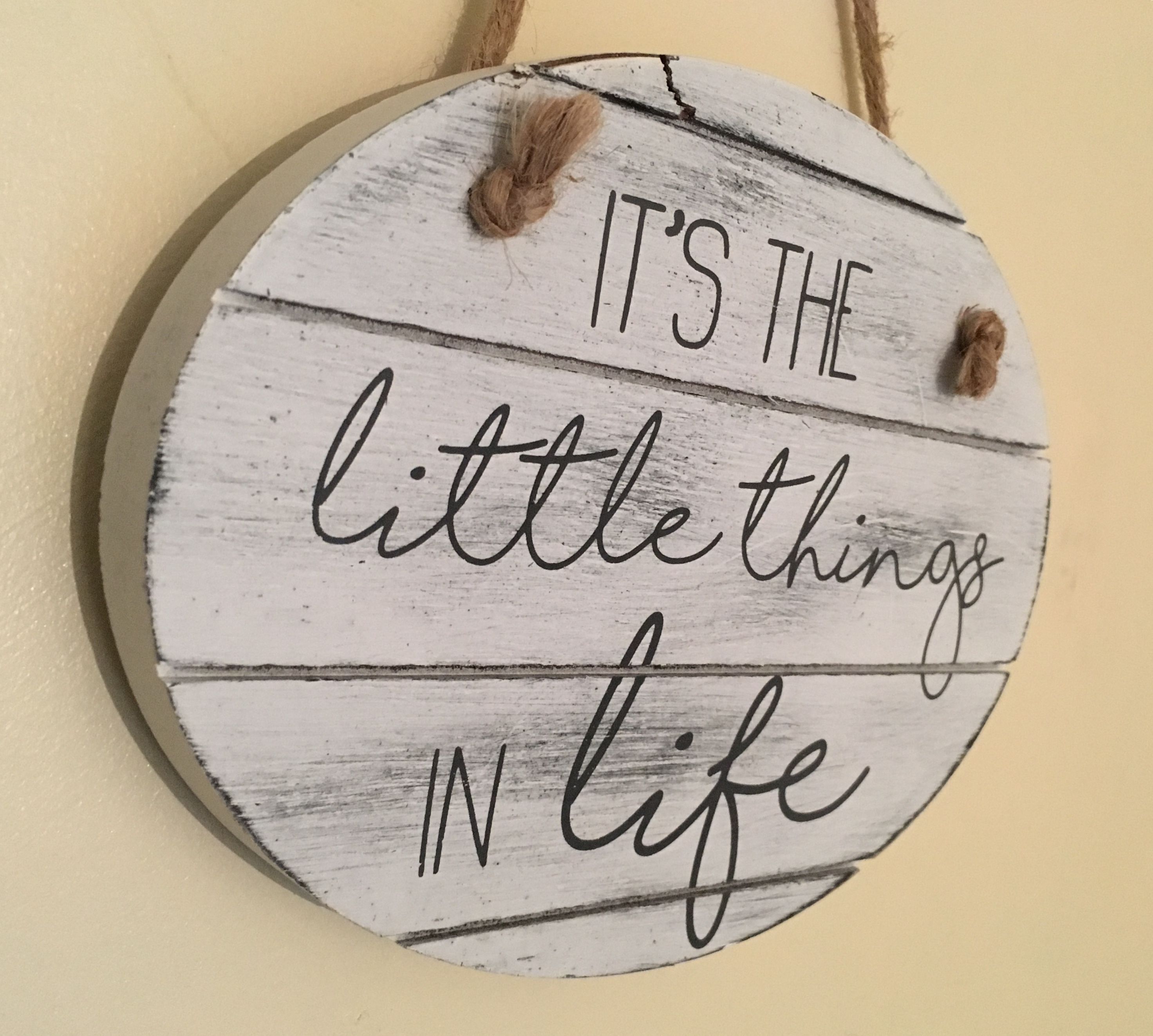 A circular wooden sign with the phrase "IT'S THE little things IN life" written on it.