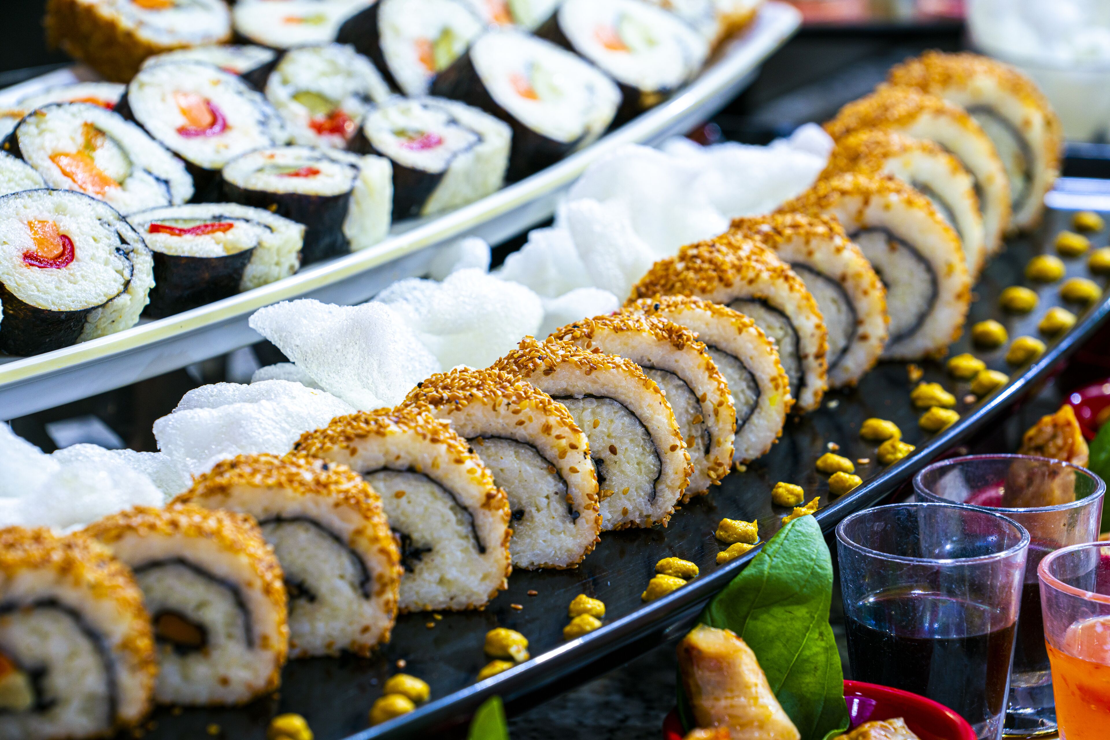 A variety of sushi rolls and drinks on a tray.