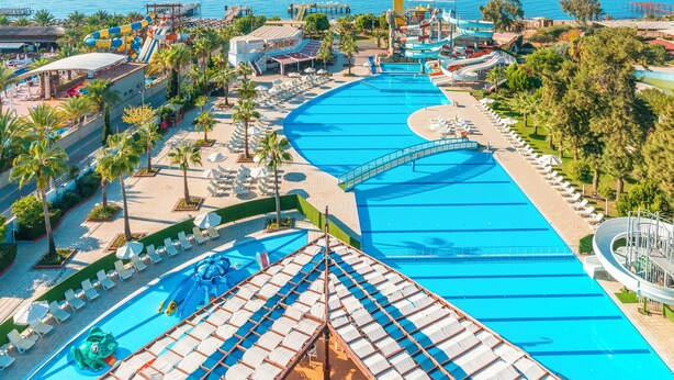 Un complex turístic amb una gran piscina, tobogans aquàtics i vistes al mar.