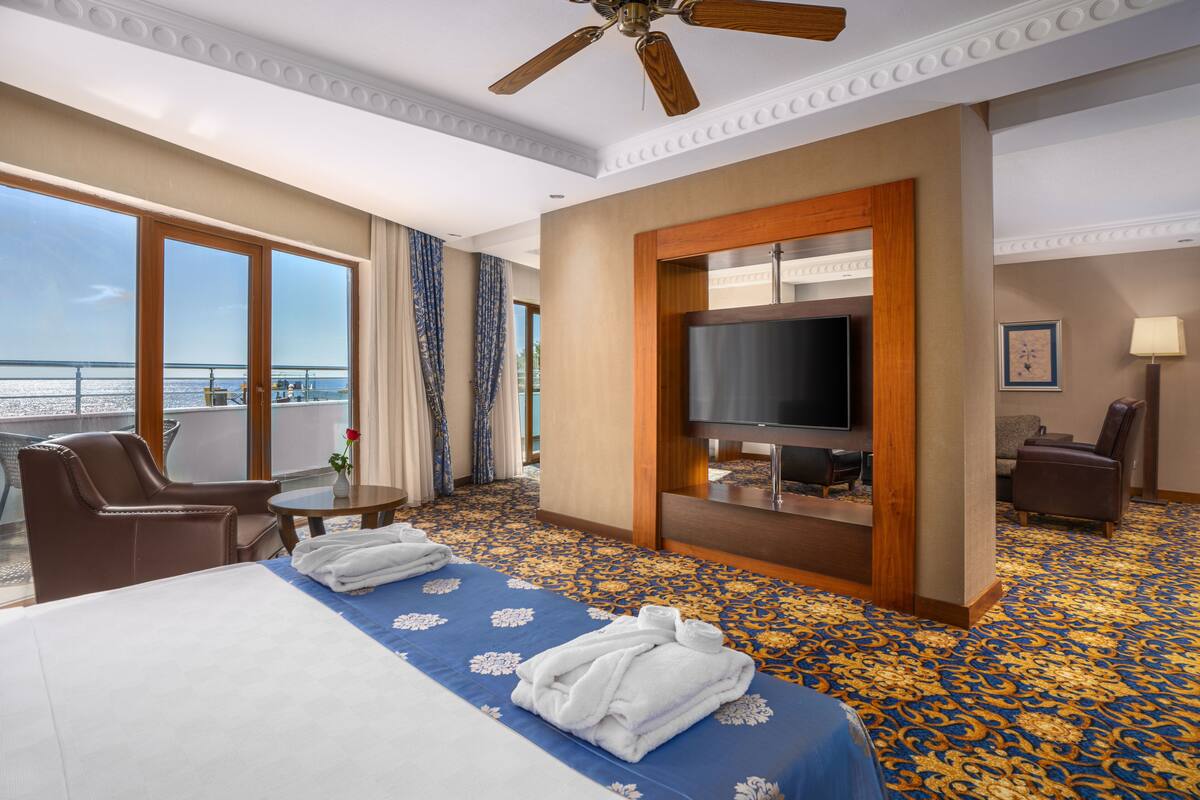 A hotel room with a large bed, a television, a desk, and a chair.