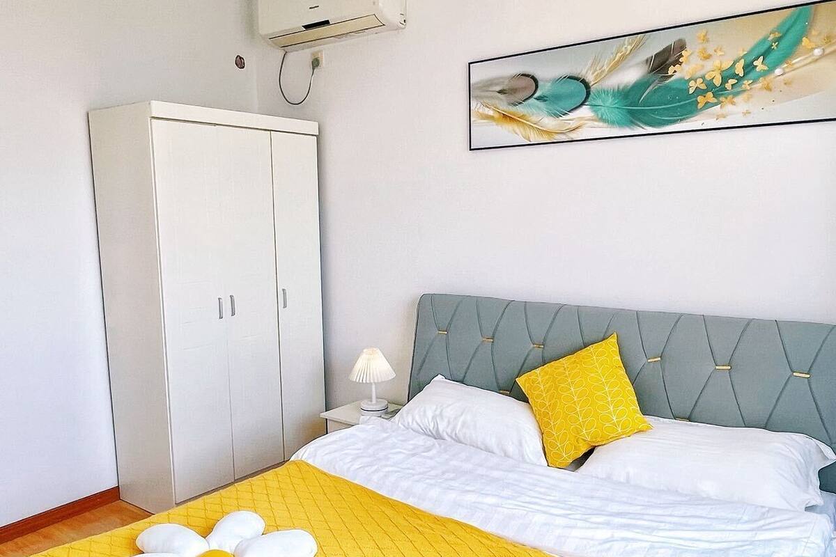 A bedroom with a bed, a nightstand, a lamp, a wardrobe, and a painting on the wall.