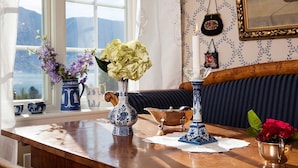 A room with a wooden table, two vases with flowers, a candle, and a framed picture on the wall.