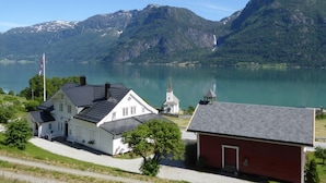 A lakeside building with a church, surrounded by mountains and a clear sky.