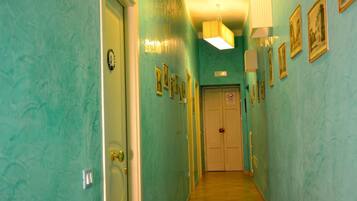 A hallway with teal walls, framed pictures, and a door with a 'no entry' sign.