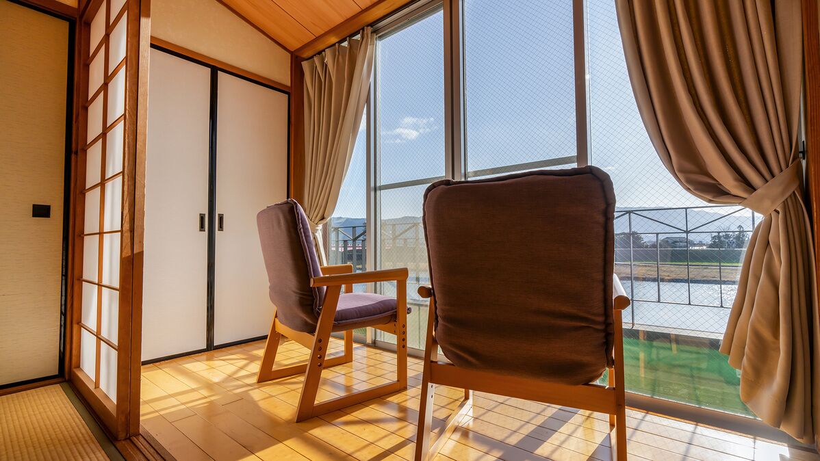 A room with tatami flooring, sliding doors, and a view of a body of water.