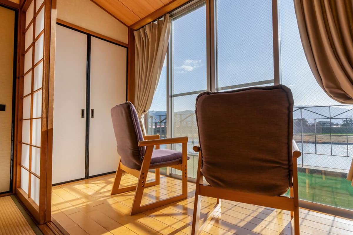 A room with tatami flooring, sliding doors, and a view of a body of water.
