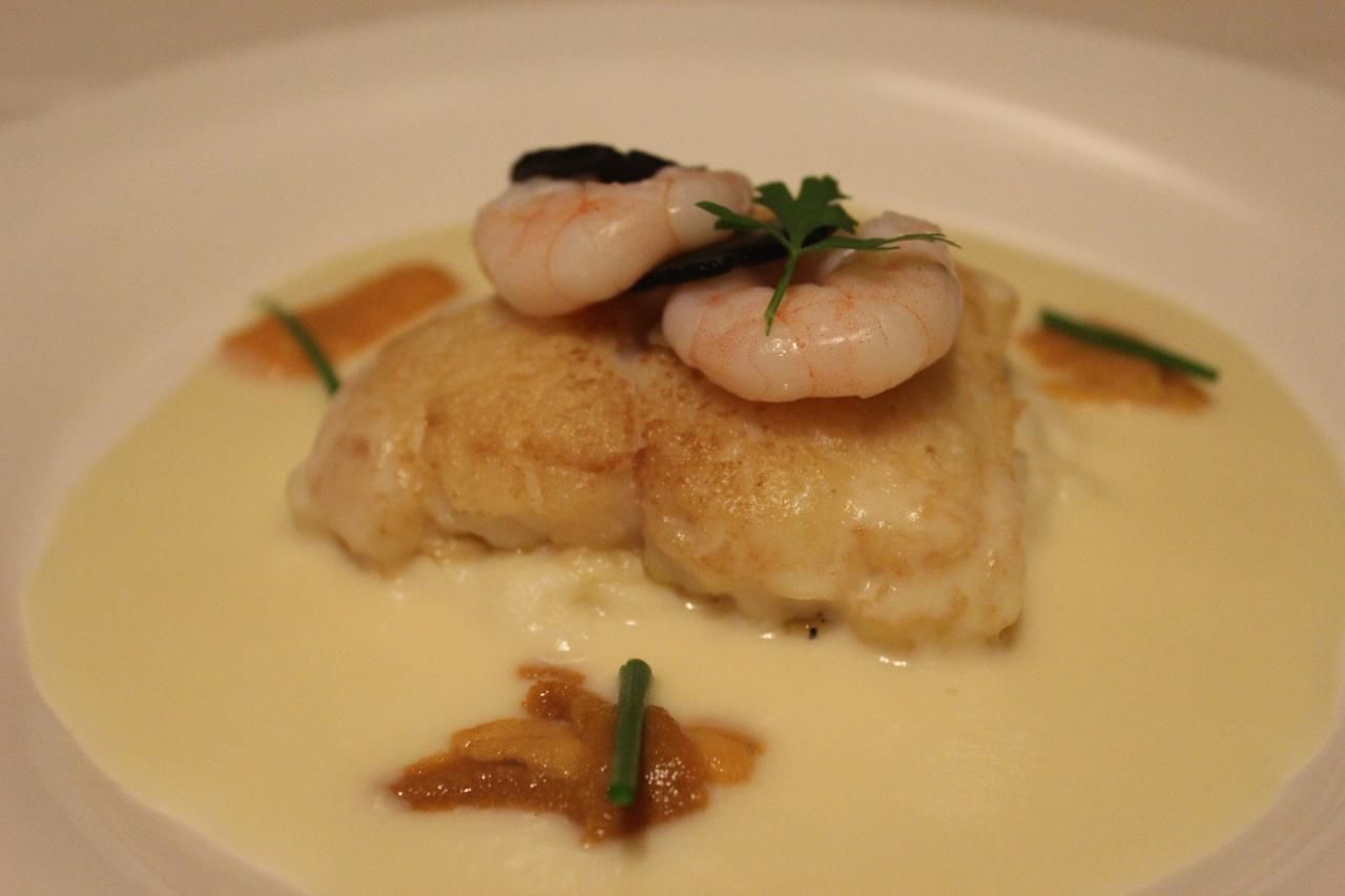 A plate of food with shrimp and a piece of fish, garnished with herbs.