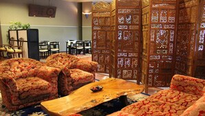 A room with floral-patterned sofas, a wooden coffee table, and traditional wooden partitions. - Enmeikan (Asakura)
