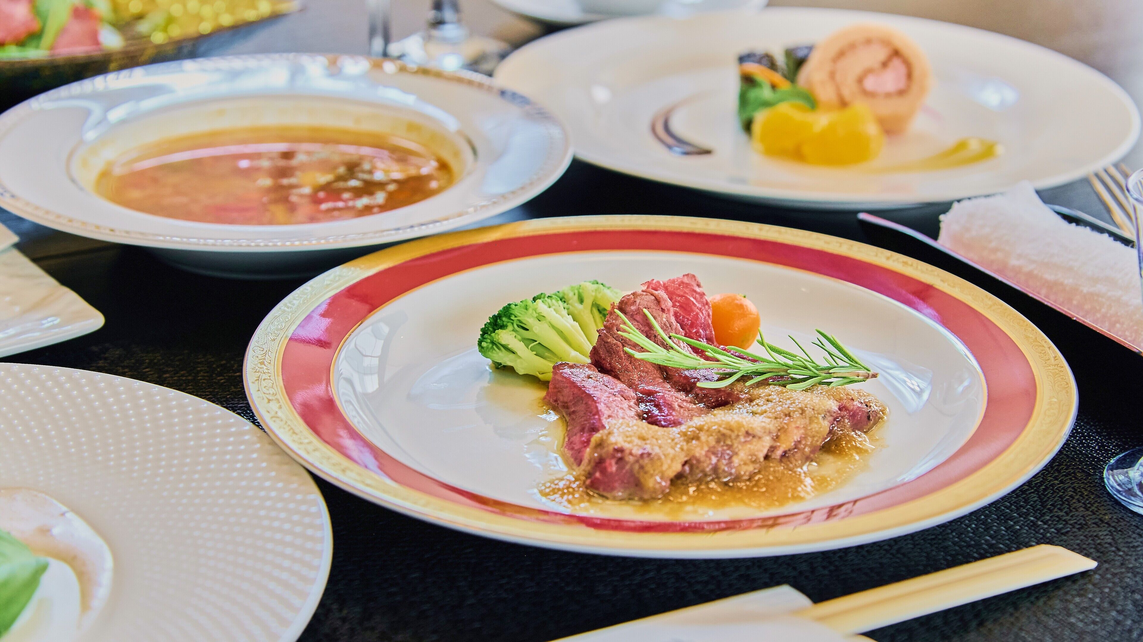 A dining table with various dishes, including a plate with meat, vegetables, and sauce.