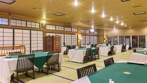 A banquet hall with multiple tables, chairs, and a traditional Japanese-style partition. - Enmeikan (Asakura)