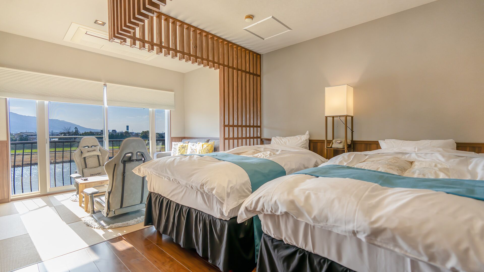 Une chambre d’hôtel avec deux lits, une chaise, une lampe et une vue sur une étendue d’eau.