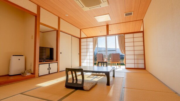 A traditional Japanese room with tatami flooring, a television, a refrigerator, and a sliding door leading to a balcony with a view of the mountains. - Enmeikan (Asakura)