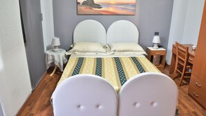 Une chambre à coucher comprenant un lit, deux tables de chevet, une chaise, une petite table et un tableau accroché au mur.