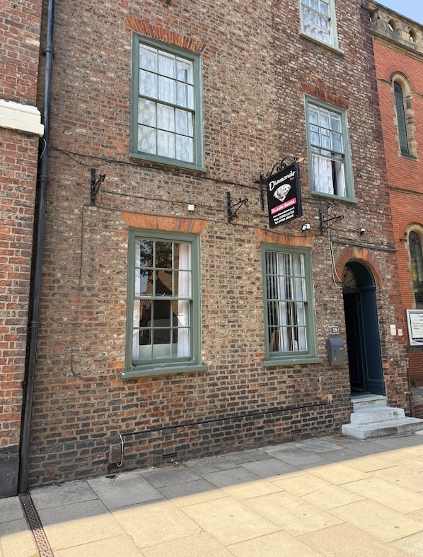 A brick building with multiple windows and a sign for 'Diamonds' indicating rooms for rent.