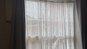 A window with patterned curtains and a view of a building outside. - Diamonds Inn Ltd (York)
