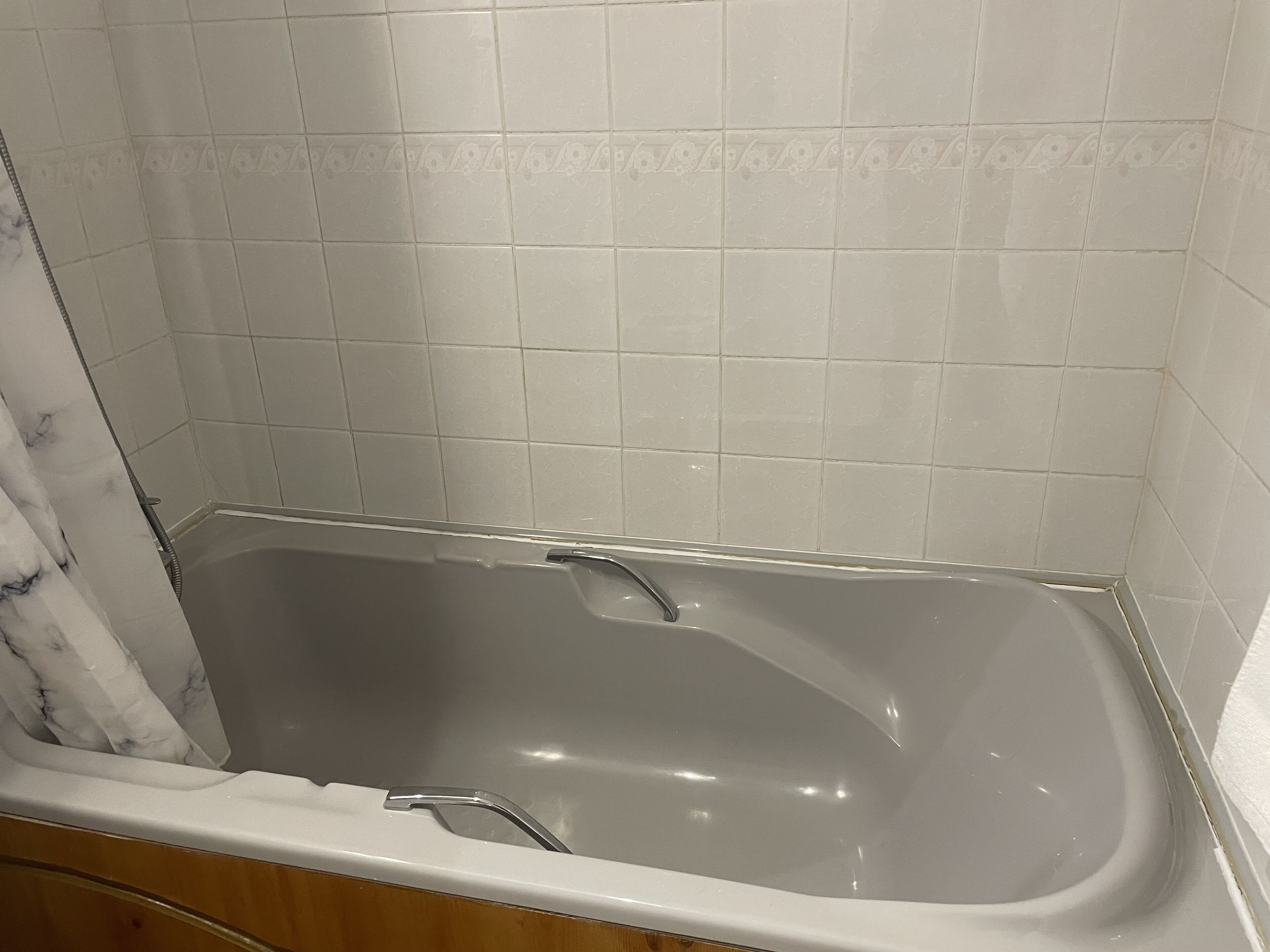 A bathroom with a bathtub, tiled walls, and wooden cabinetry.