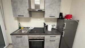 A compact kitchen with grey cabinets, a built-in oven, a sink, and a refrigerator. - A Quattro Passi Da (Rome)