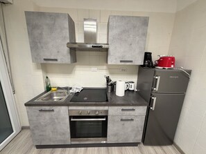 A compact kitchen with grey cabinets, a built-in oven, a sink, and a refrigerator. - A Quattro Passi Da (Rome)