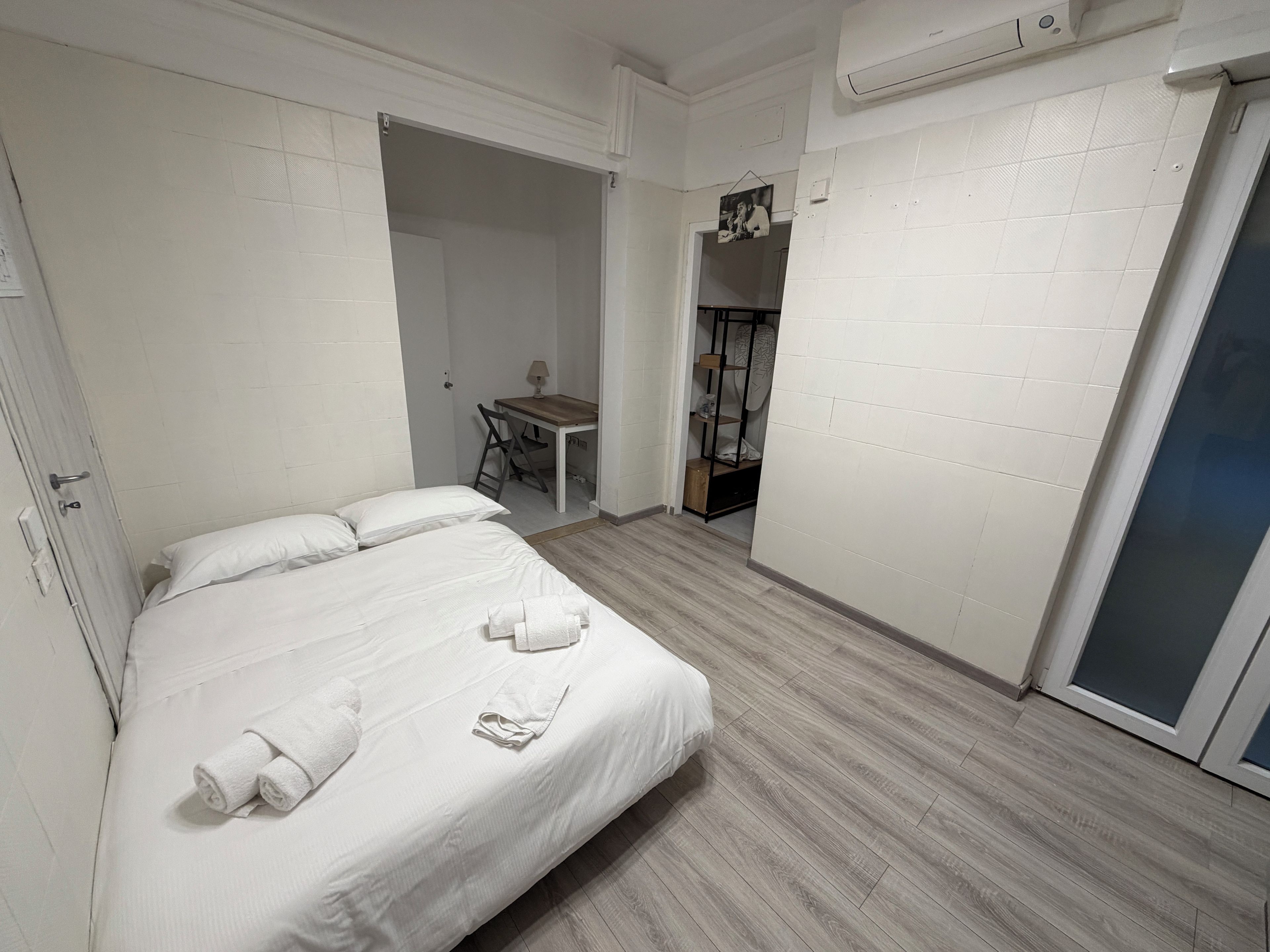 A hotel room with a bed, a desk, and a wardrobe.
