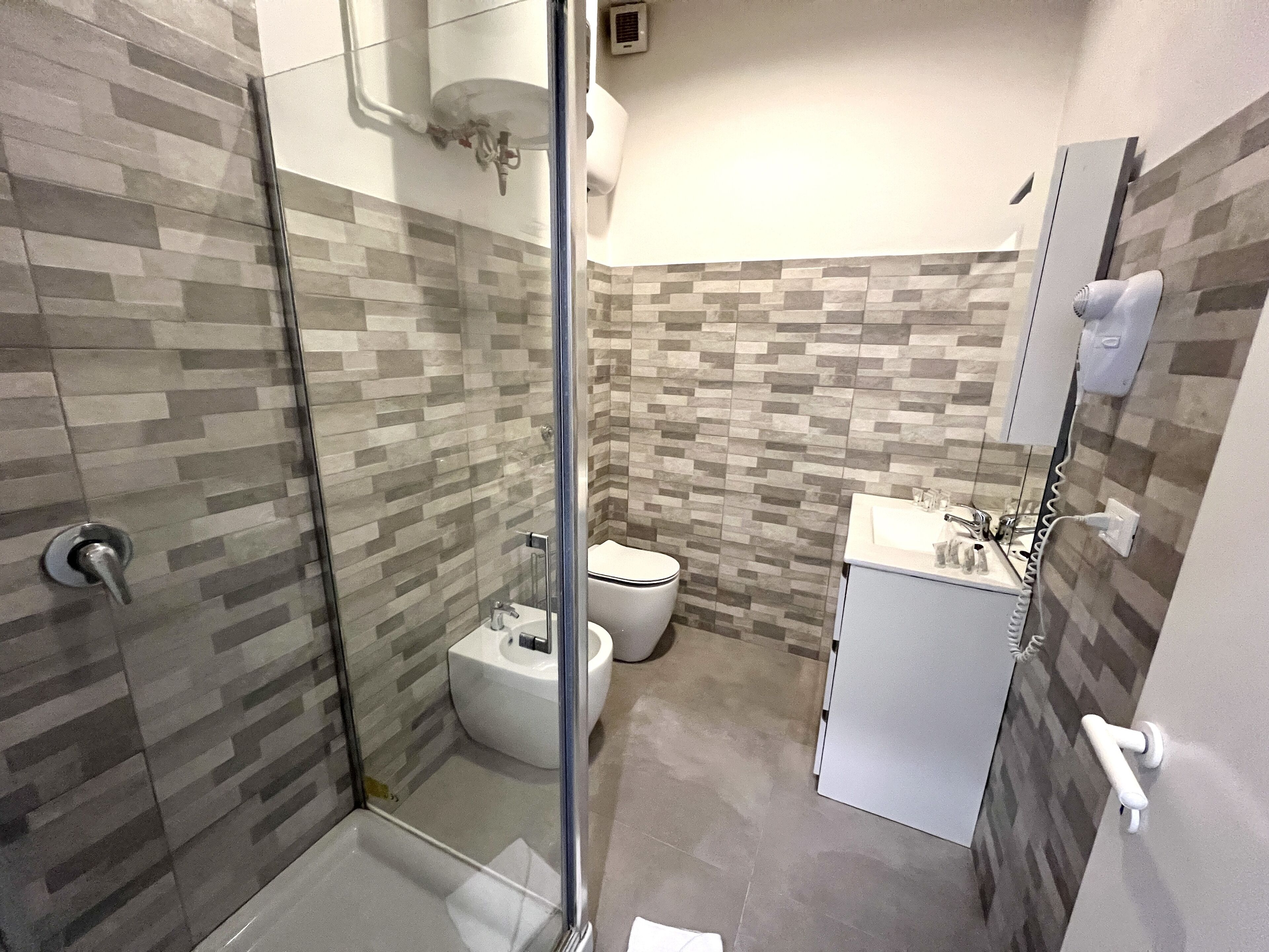 A modern bathroom with a glass shower enclosure, a toilet, and a sink with a mirror.