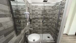 A modern bathroom with a glass-enclosed shower, a large sink, and a towel on the floor. - A Quattro Passi Da (Rome)