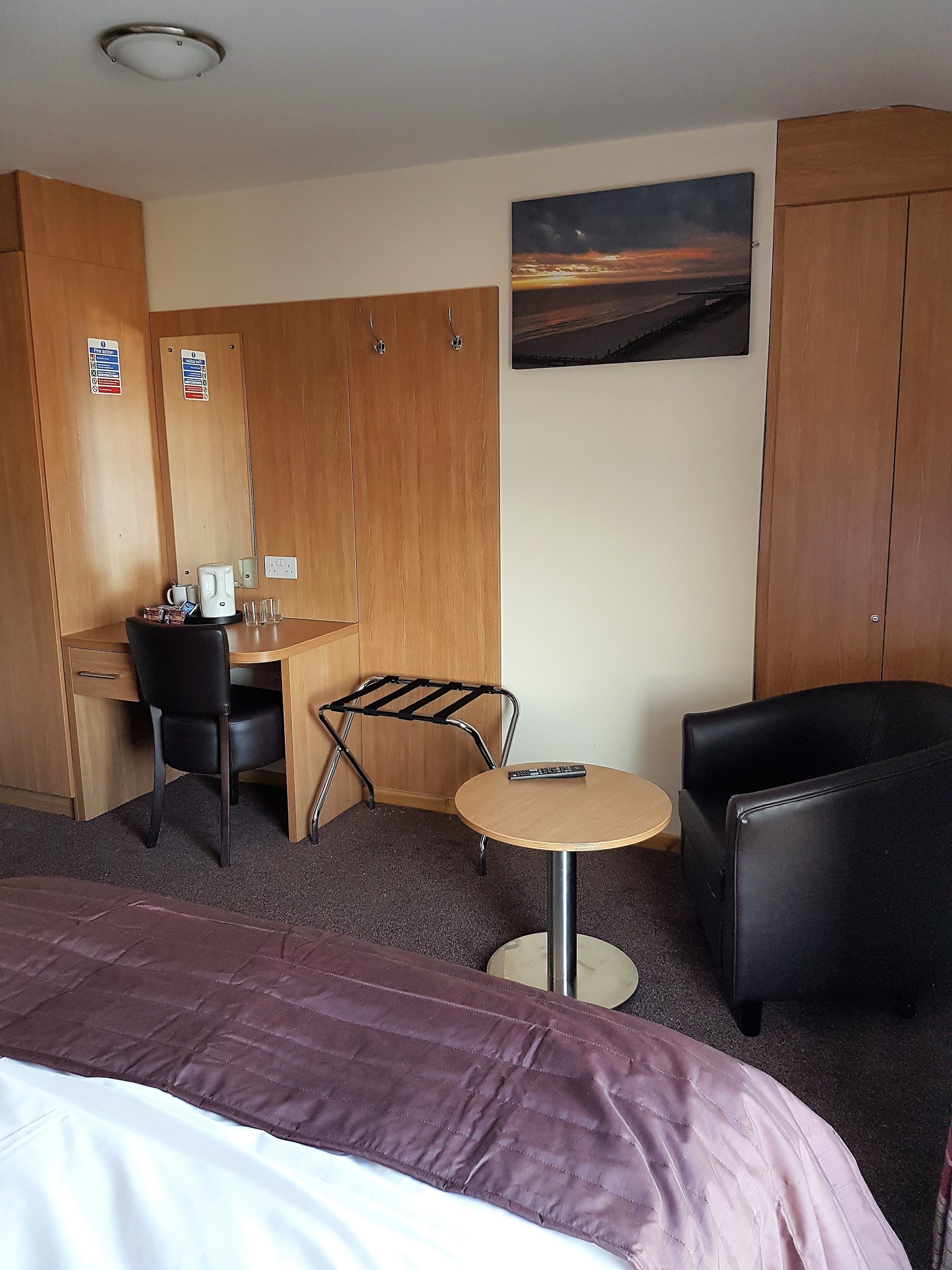 A hotel room with a bed, a desk, a chair, a small table, and a couch.