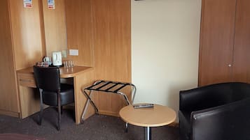 A hotel room with a bed, a desk, a chair, a small table, and a couch.